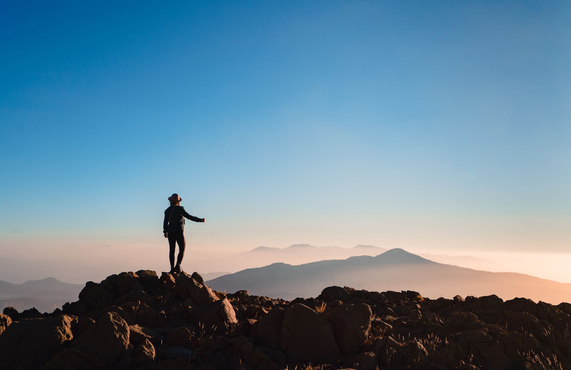 Silhouette of a climber woman  is  watching  sunrise on the top of a mountain